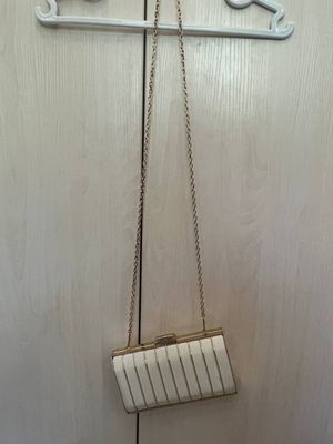 Белая сумка с золотистыми линиями.