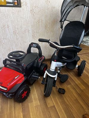 Detskiy velisoped va yonidagi mashina padarka