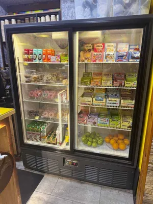 Большой витринный холодильник с подсветкой и раздвижными дверями.